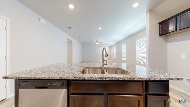 kitchen featuring dark brown cabinetry, ceiling fan, dishwasher, sink, and light stone counters