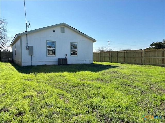 back of property with central air condition unit and a yard