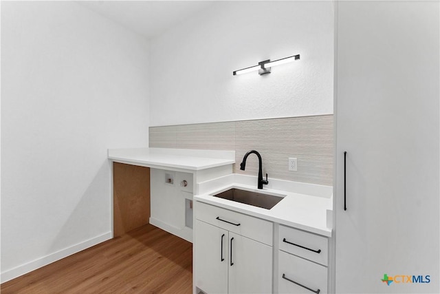 clothes washing area with cabinets, sink, and light hardwood / wood-style flooring