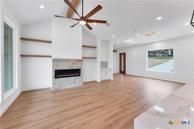 unfurnished living room featuring a stone fireplace, vaulted ceiling, ceiling fan, and light wood-type flooring