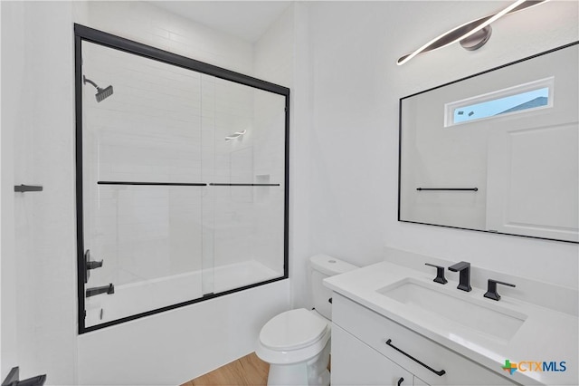 full bathroom with vanity, hardwood / wood-style flooring, enclosed tub / shower combo, and toilet