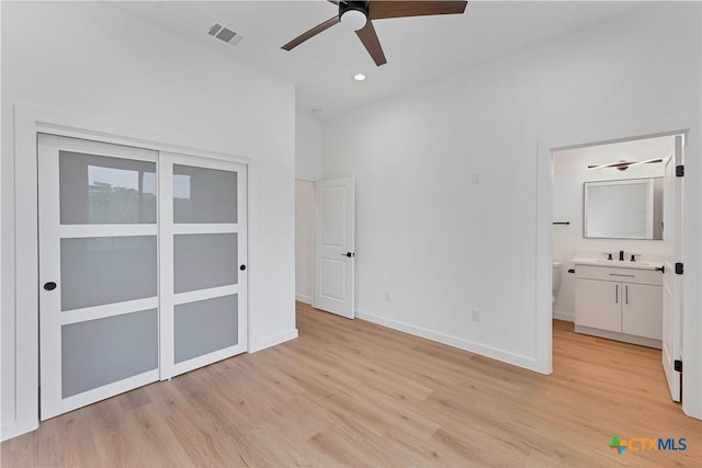 unfurnished bedroom featuring connected bathroom, light hardwood / wood-style floors, and sink