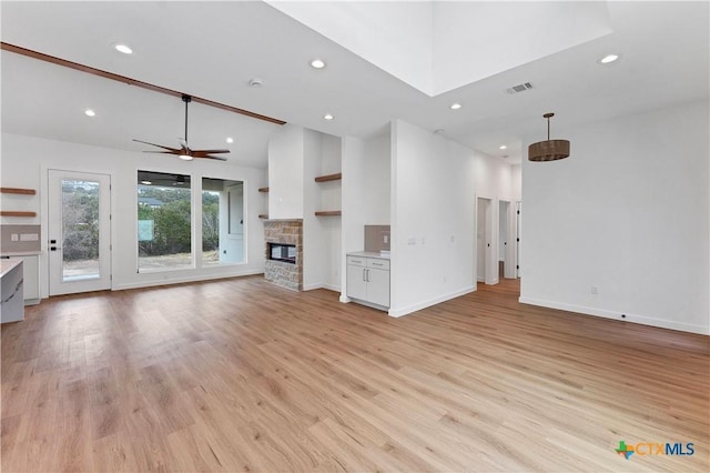 unfurnished living room with ceiling fan, high vaulted ceiling, light wood-type flooring, and a fireplace