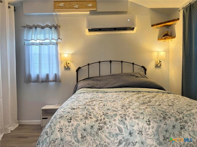 1008 W Dallas Ave, Seadrift, TX 77983 - bedroom with a wall mounted air conditioner, wood finished floors, and baseboards