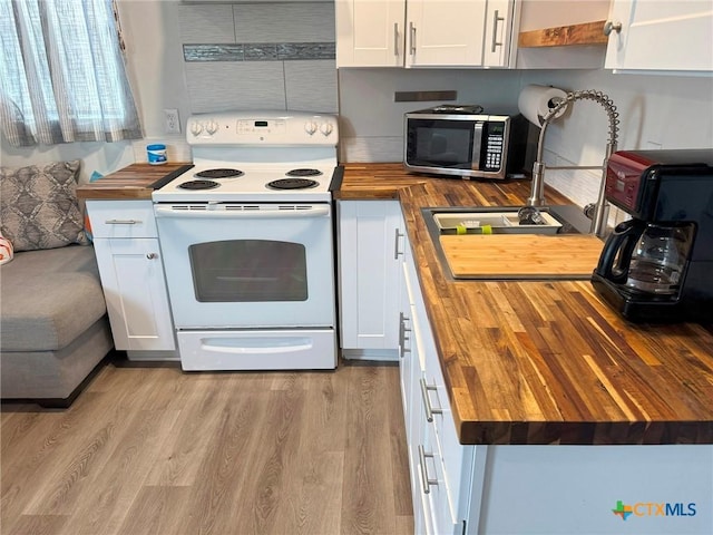 1008 W Dallas Ave, Seadrift, TX 77983 - kitchen with light wood finished floors, white cabinetry, stainless steel microwave, butcher block countertops, and white electric range