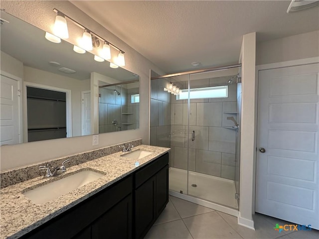 907 James Parker Cir, Killeen, TX 76542 - full bathroom with tile patterned flooring, a shower stall, double vanity, a spacious closet, and a textured ceiling