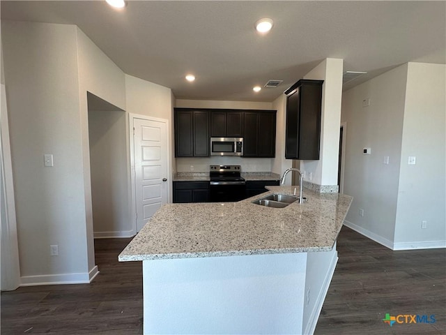 907 James Parker Cir, Killeen, TX 76542 - kitchen with stainless steel microwave, range with electric stovetop, light stone counters, a peninsula, and dark wood-style flooring