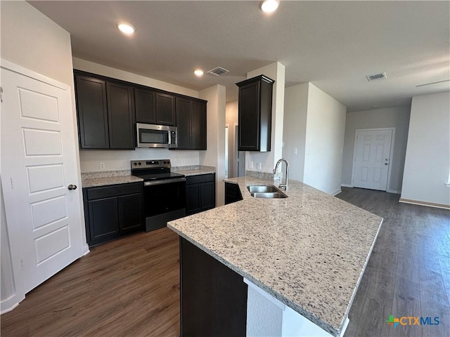 907 James Parker Cir, Killeen, TX 76542 - kitchen with electric range, stainless steel microwave, dark wood-style flooring, a peninsula, and light stone counters