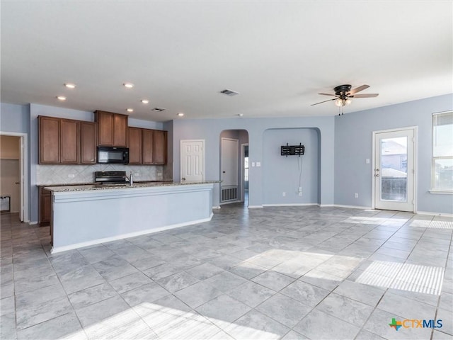 kitchen featuring tasteful backsplash, a center island with sink, ceiling fan, and black appliances