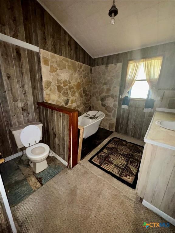 235 Murray Ln, Gatesville, TX 76528 - bathroom featuring toilet, vaulted ceiling, vanity, and wooden walls