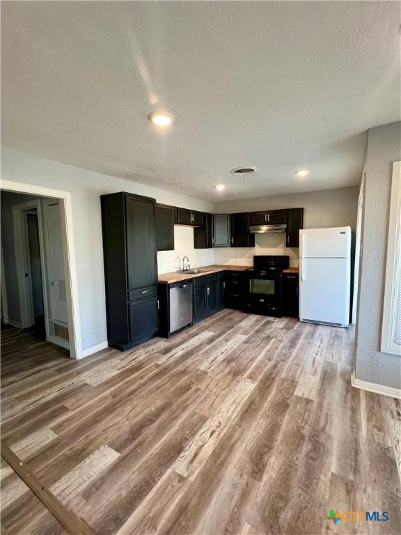 kitchen featuring dishwasher, wood-type flooring, black electric range, and white fridge