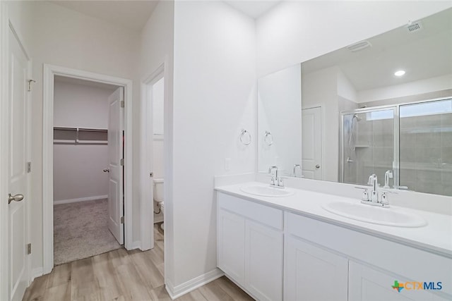 bathroom with toilet, hardwood / wood-style floors, a shower with door, and vanity