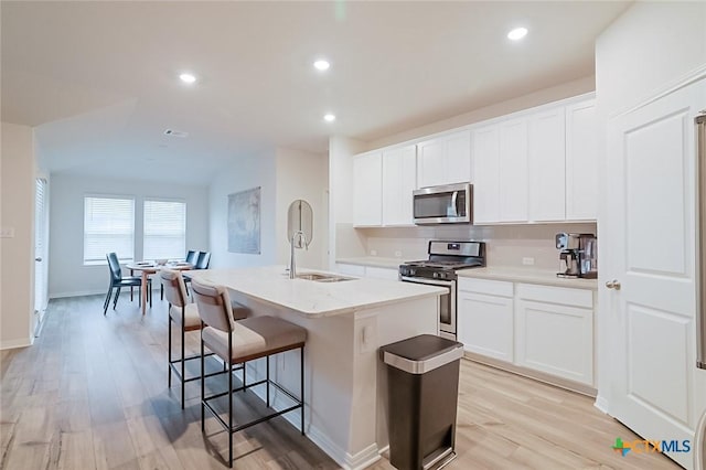 kitchen with sink, white cabinets, a center island with sink, and stainless steel appliances