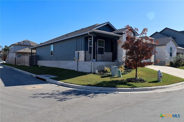 view of front facade with covered porch, fence, concrete driveway, and a front yard