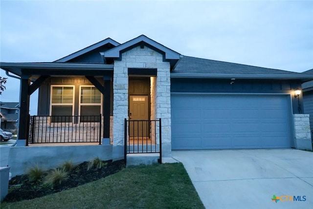 view of front of property with concrete driveway, covered porch, a garage, and stone siding