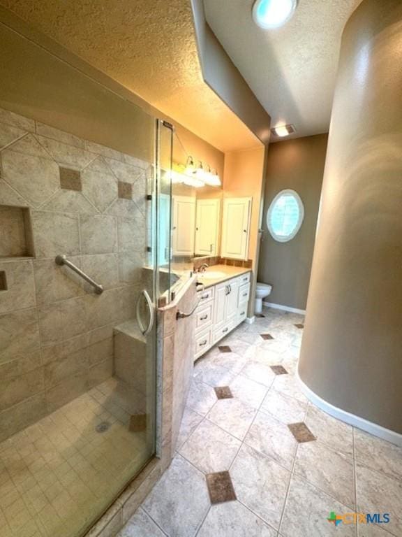 2772 Cloisters Dr, College Station, TX 77845 - bathroom featuring double vanity, a shower stall, and a textured ceiling