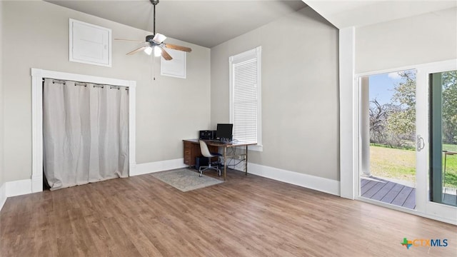 unfurnished office featuring baseboards, a healthy amount of sunlight, wood finished floors, and a ceiling fan