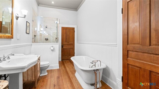 bathroom featuring a shower stall, a soaking tub, wood finished floors, and wainscoting