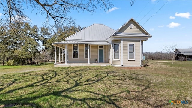 back of property with a yard, covered porch, metal roof, and a standing seam roof