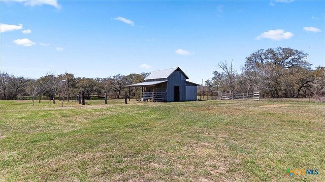 view of yard with a rural view, an outdoor structure, an outbuilding, and fence