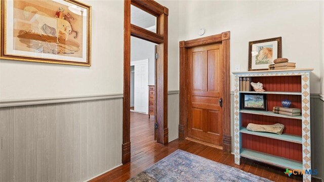 corridor with a wainscoted wall and wood-type flooring