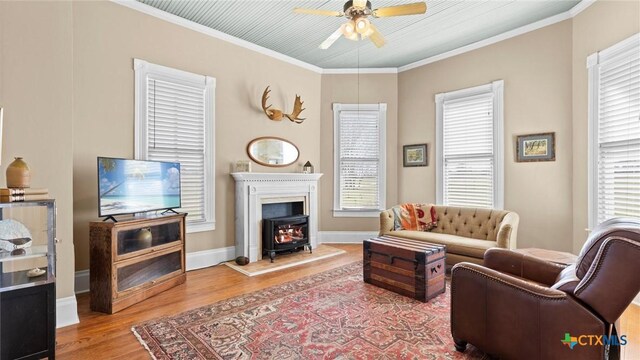 living area with a ceiling fan, a healthy amount of sunlight, wood finished floors, and ornamental molding