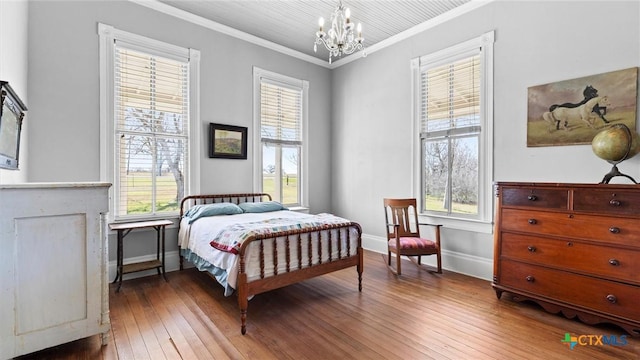 bedroom with hardwood / wood-style floors, crown molding, a notable chandelier, and baseboards