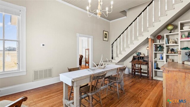 dining area with visible vents, an inviting chandelier, wood finished floors, and stairs