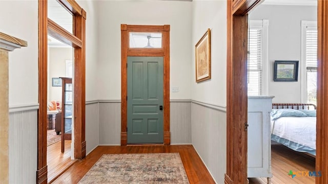 foyer entrance with wood finished floors and a wainscoted wall