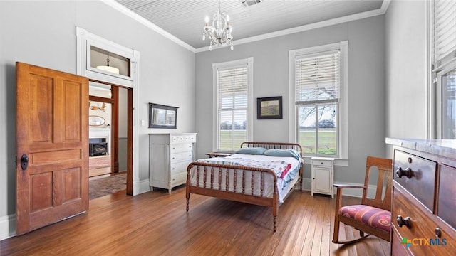 bedroom with hardwood / wood-style floors, crown molding, and an inviting chandelier