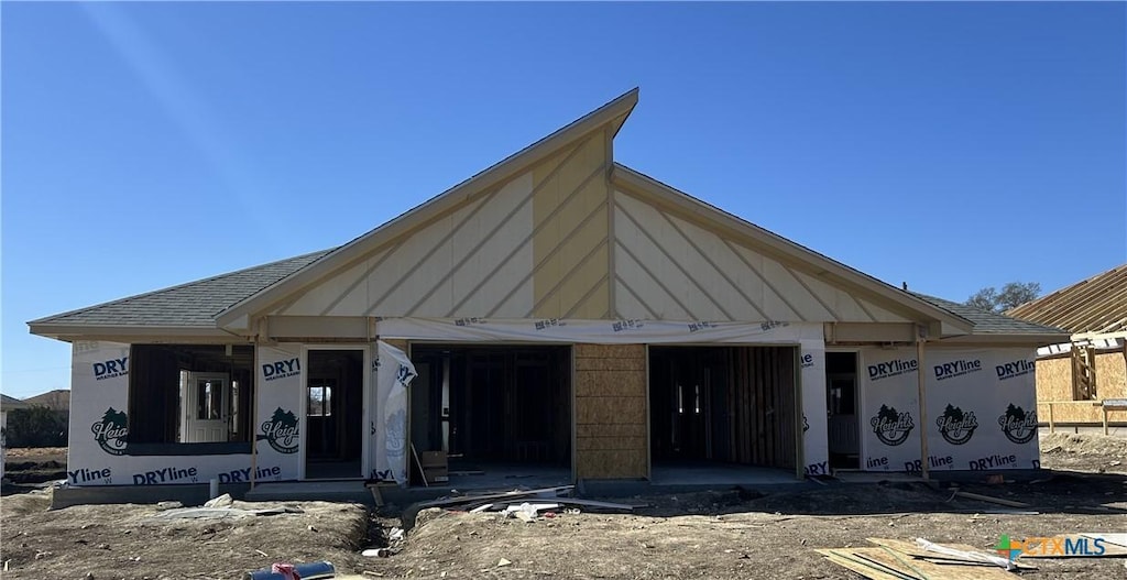 unfinished property featuring a garage and roof with shingles