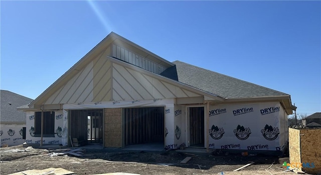 unfinished property with a garage and roof with shingles