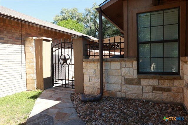 view of home's exterior featuring fence, a gate, and stone siding