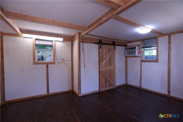 basement with a healthy amount of sunlight, a wall unit AC, a barn door, and wood finished floors