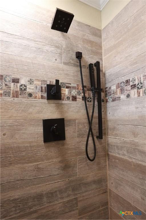 full bathroom featuring crown molding and tiled shower