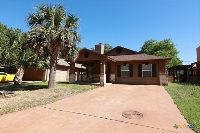 ranch-style home with a front lawn, stone siding, ceiling fan, and a chimney