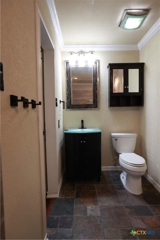 half bath featuring vanity, baseboards, toilet, ornamental molding, and stone tile floors