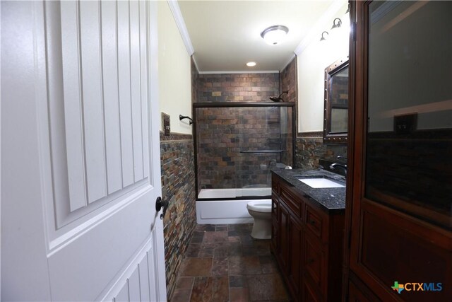 bathroom featuring crown molding, vanity, toilet, stone finish floor, and enclosed tub / shower combo