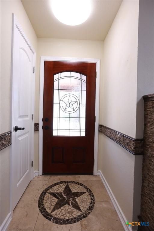 doorway featuring baseboards and tile patterned floors