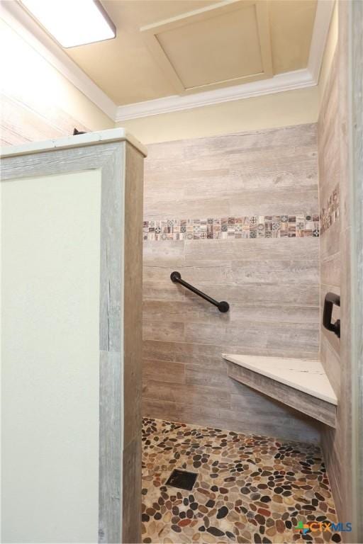 full bath featuring crown molding, stone finish flooring, and a tile shower