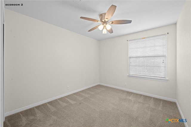 unfurnished room featuring baseboards, light carpet, and a ceiling fan