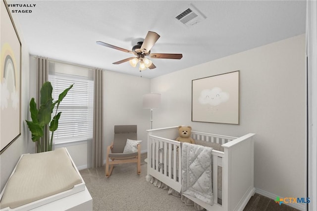 bedroom featuring a nursery area, baseboards, visible vents, and ceiling fan