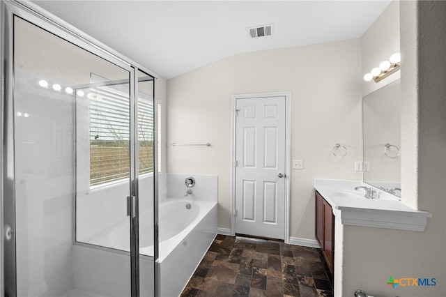 bathroom featuring visible vents, a garden tub, lofted ceiling, stone finish floor, and vanity