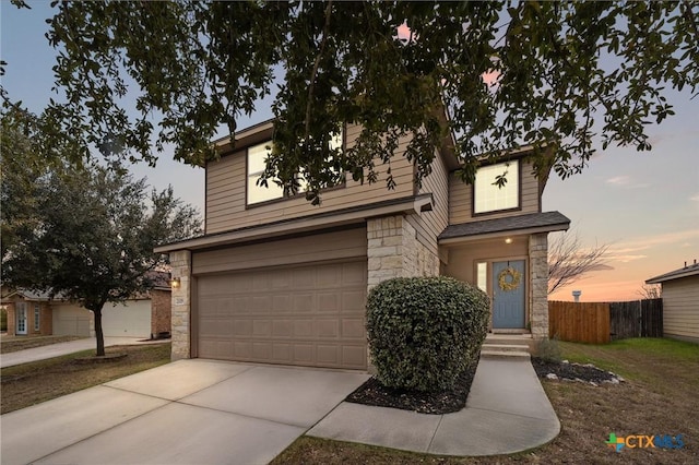 view of front of property with concrete driveway, a garage, fence, and stone siding