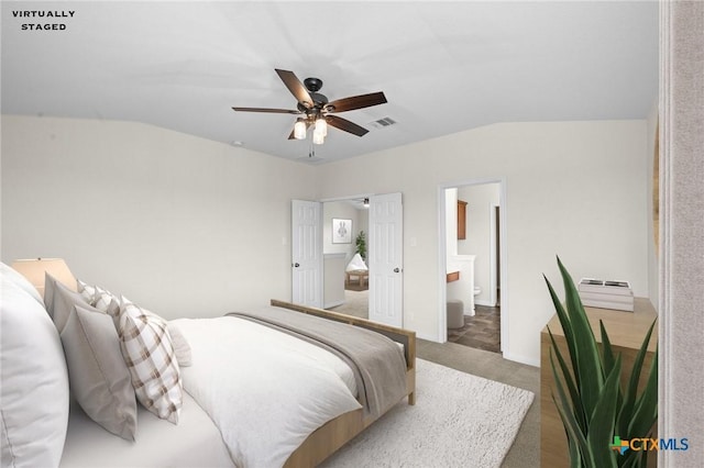 bedroom with a ceiling fan, visible vents, vaulted ceiling, light colored carpet, and connected bathroom