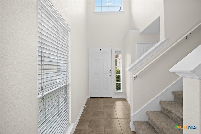 entrance foyer featuring tile patterned flooring, plenty of natural light, baseboards, and stairs