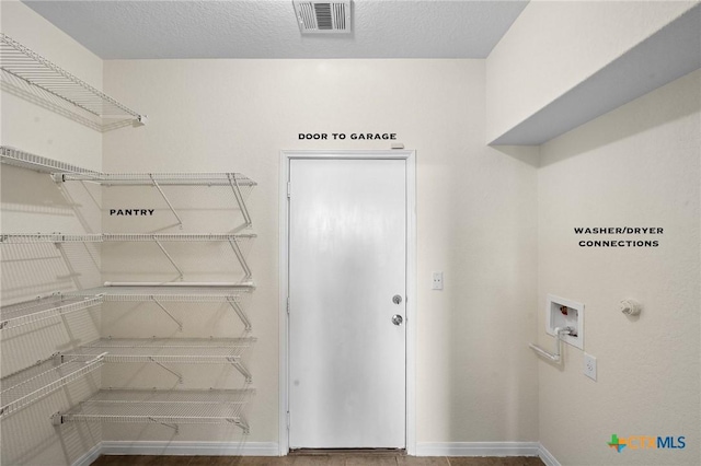 washroom featuring visible vents, baseboards, laundry area, hookup for a washing machine, and a textured ceiling