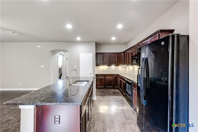 1202 Jester Ct, Copperas Cove, TX 76522 - kitchen with black appliances, arched walkways, dark wood finished floors, backsplash, and dark stone countertops