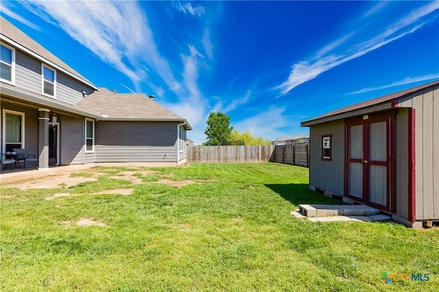 view of yard with an outbuilding, a fenced backyard, and a storage unit