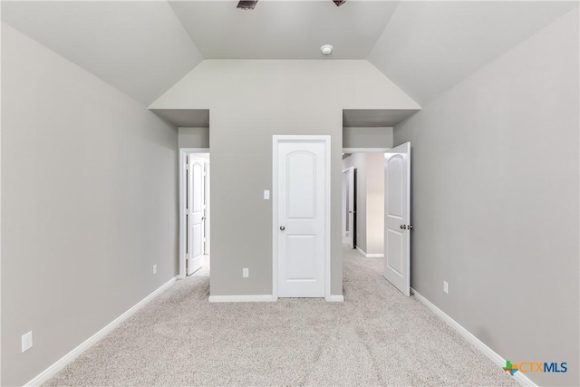 unfurnished bedroom with carpet flooring, baseboards, and lofted ceiling